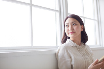 窓に寄りかかる若い女性