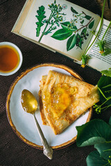 dandelion jam and honey in a spoon on a table with botanical illustrations