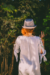  woman with hat turned back touching trees in secret garden