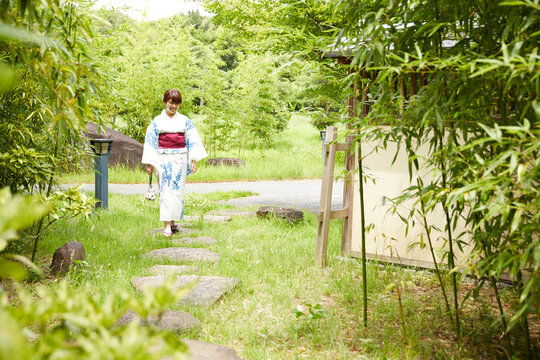 日本庭園を歩く浴衣の女性