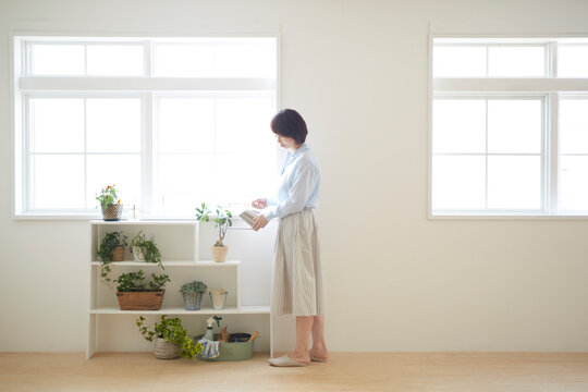 室内植物に水をあげている女の人