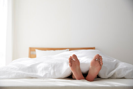 明るい光の入ったシンプルなベッドルームと眠る男性