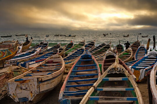West Africa. Mauritania. The sandy shore of the Atlantic Ocean with wooden painted boats, on which local fishermen go to sea every day to catch fish. Each boat has a unique design and painting.