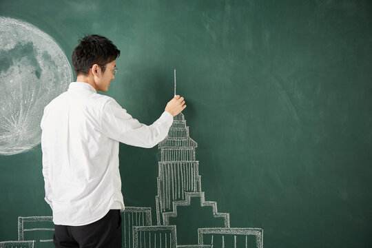 満月が描かれた黒板にビル群のイラストを描く