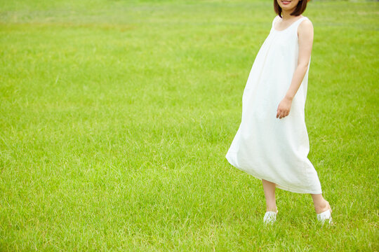 草原の中白い布を持ち微笑む若い女性