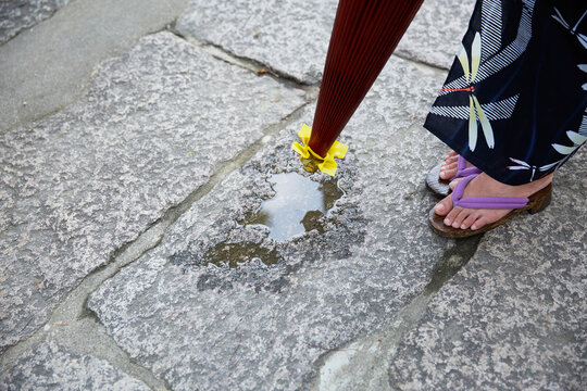 水たまりと、和傘を持った浴衣の女性