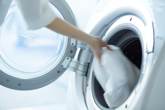 ドラム式洗濯機に洗濯物を入れる女性の手