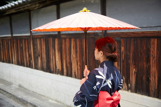 和傘を差して路地を歩く女性