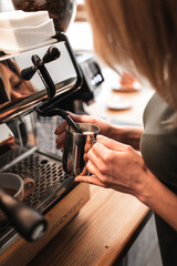Closeup image of hands pouring milk and preparing fresh cappuccino, coffee artist and preparation concept, morning coffee