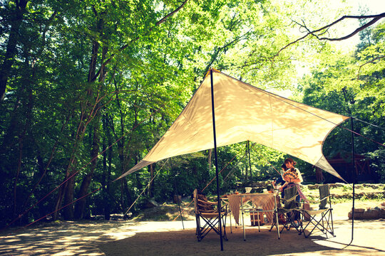 森に貼られたタープと女性