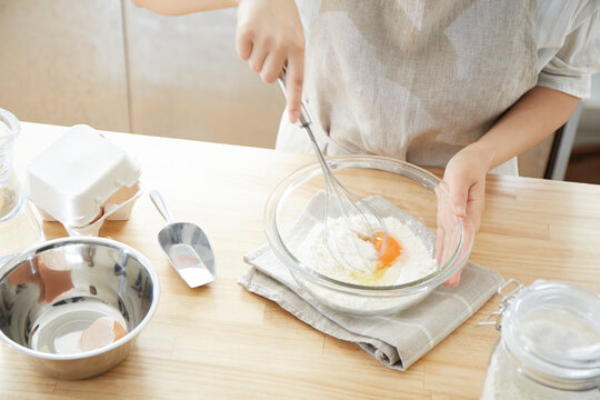 キッチンカウンターで材料をミキサーで混ぜる女性