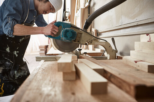 押し切りで木材を切る男性