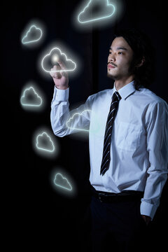 宙に浮いたクラウドマークをタッチするサラリーマン