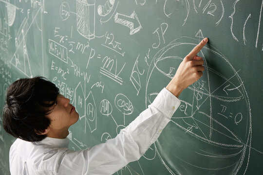 黒板に書かれた数式に指を指す