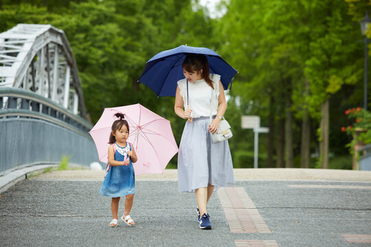 傘を差しながら歩く母と子