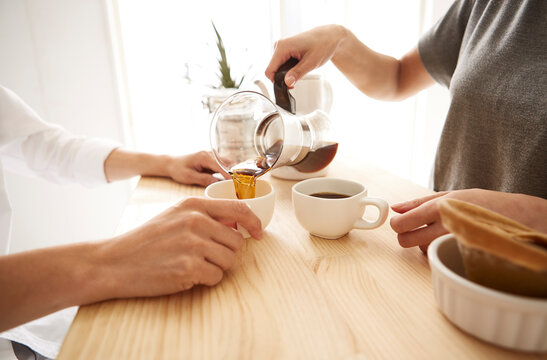 キッチンカウンターでコーヒーを注ぐ男女の手元
