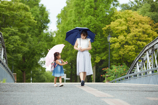 傘を差しながら歩く母と子