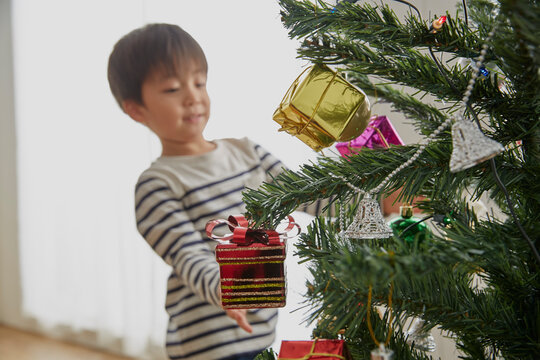 クリスマスツリーの飾り付けをする男の子