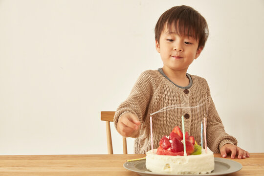 お祝いのケーキのろうそくの火を吹き消して満足そうな顔をしている男の子