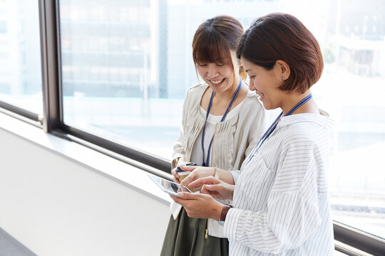 オフィスの窓際で会話するOL