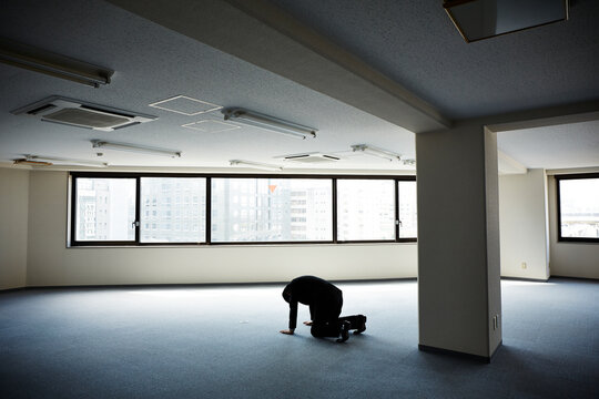 何もないオフィスで両手両膝をつき落ち込む男性