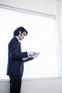 会社の窓際で資料を見る男性