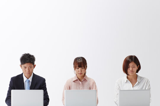 パソコンの前に一列に並んで座る3人の男女