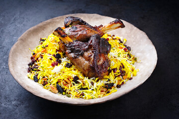 Traditional Persian tahdig jeweled javaher polow bride basmati rice with slow cooked lamb shank served as close-up on a rustic design plate with copy space © HLPhoto
