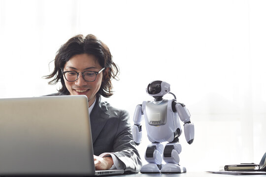 ロボットとパソコンを見るスーツを着た男性 - Powered by Adobe