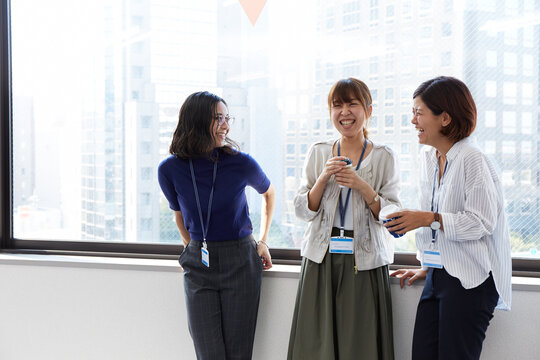 オフィスの窓際で会話するOL