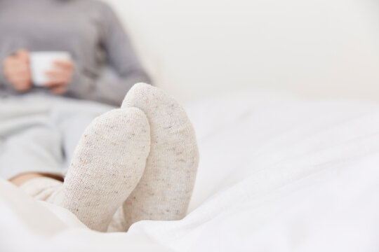 ベッドの上に座ってカップを持つ女性