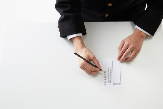 投票用紙に記入する男子学生の手元