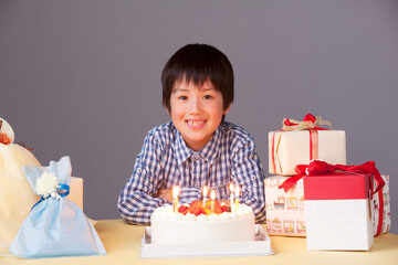 6歳のお誕生日でケーキのキャンドルの火をふく男の子