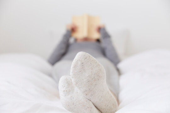 ベッドで寝ながら本を読む女性