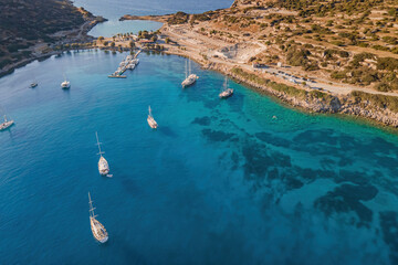 Obraz premium Yachts and sailing boatsin bay with a turquoise and transparent sea. Top view of the sailing boats in blue lagoon
