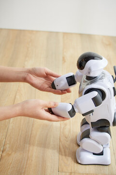 女性に手を握られているロボット