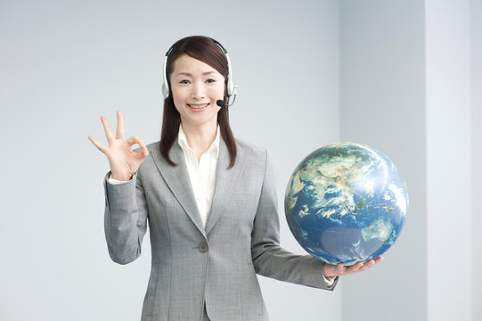 地球儀を持ちサインを出すビジネスウーマン
