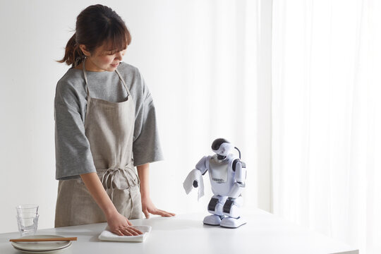 ロボットと食卓を拭く女性