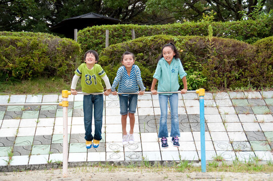 公園の鉄棒で遊ぶ子供男女３人