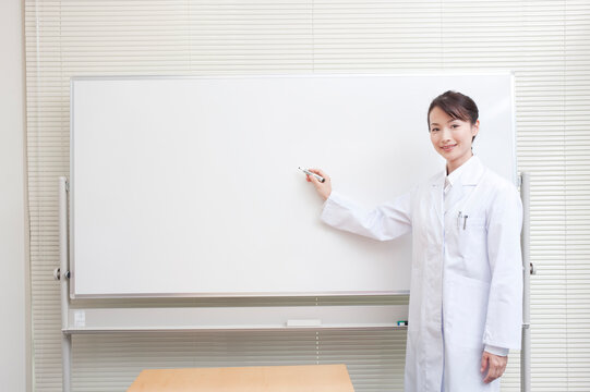 ホワイトボードで説明をする白衣を着た女医