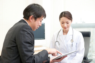 診察室でタブレットPCで情報提供するＭＲと女医