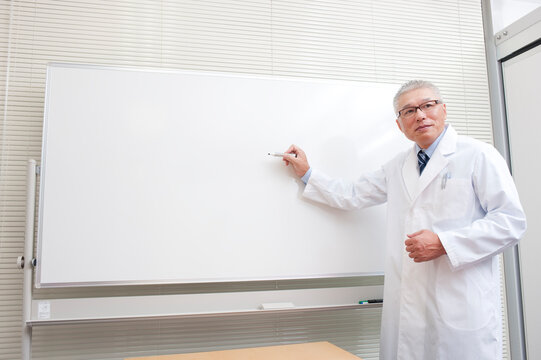 ホワイトボードで説明をする白衣を着た医者