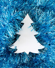 Christmas tree creative copy space against sparkling tinsel decoration in icy blue and silver colour. Winter background. New Year or Christmas concept. Minimal flat lay.