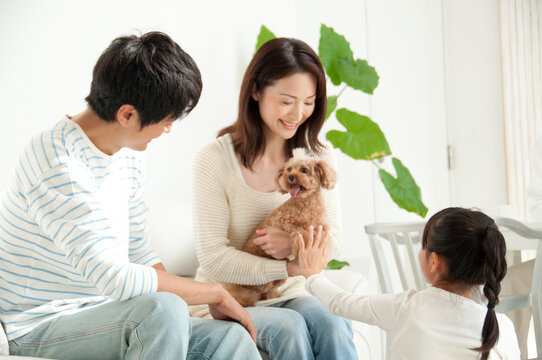 ソファに座った夫婦と女の子の家族と犬