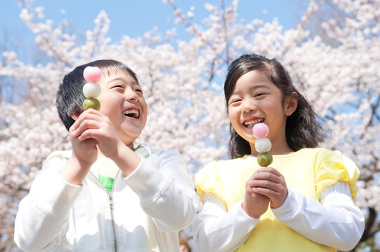 桜と花見だんごを持つ小学生男女