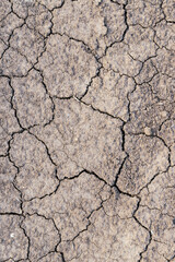 Cracked earth texture of ground, broken and rough surface gray mud clay soil in summer season, cracked ground floor on arid drought environment