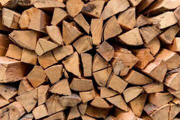 Background of dry chopped logs firewood used as a decor. The pile of beech logs outdoor ready for winter and heating