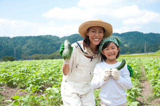 畑の中で収穫した作物を持つ母と女の子
