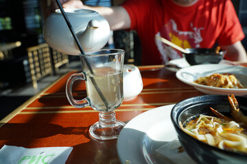 
a man pours hot mulled wine from a teapot into a mug on white wine in a cafe