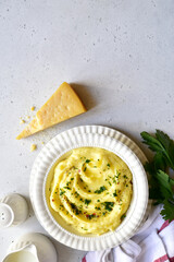 Mashed potato with parmesan cheese and herb in a white bowl . Top view with copy space.